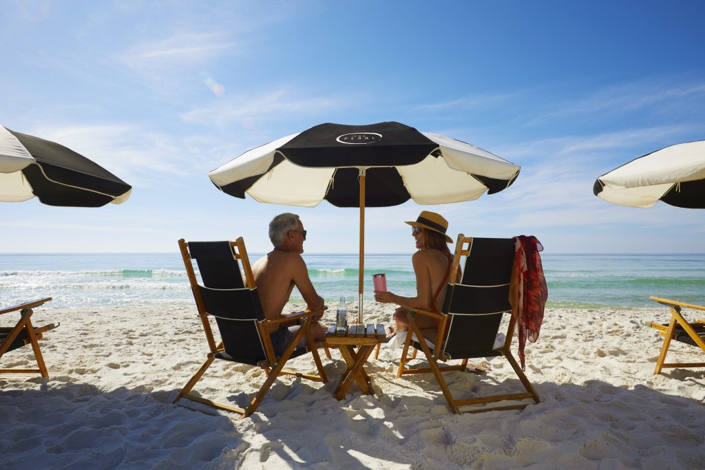 two people sitting under umbrellas on the beach 