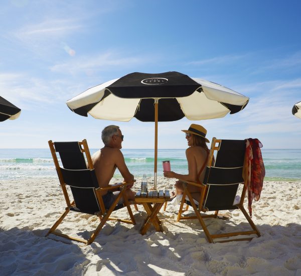 two people sitting under umbrellas on the beach