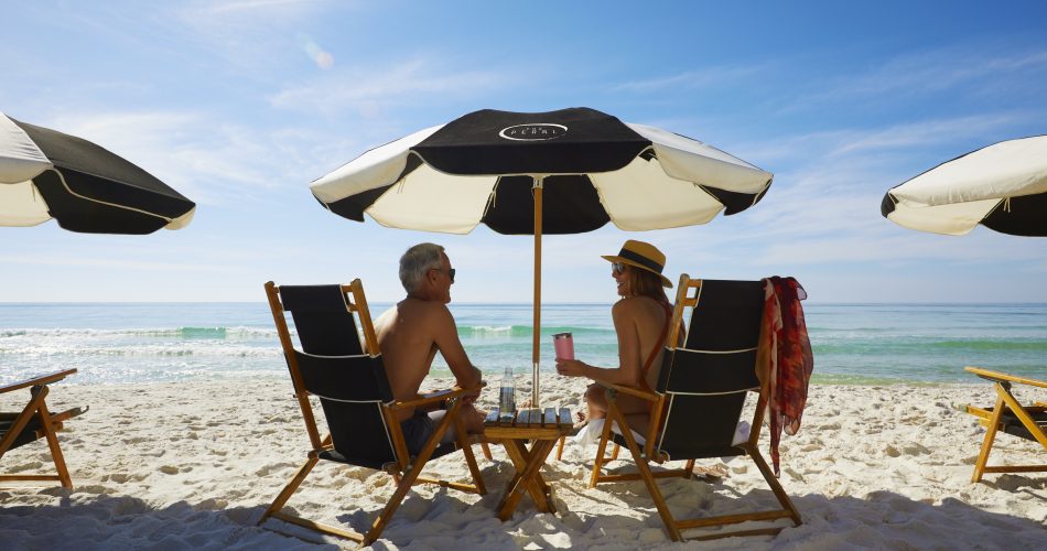 two people sitting under umbrellas on the beach