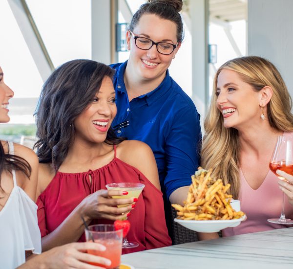 A group of women enjoying food and drinks at Fish Out of WaterColor Restaurant in South Walton, Florida