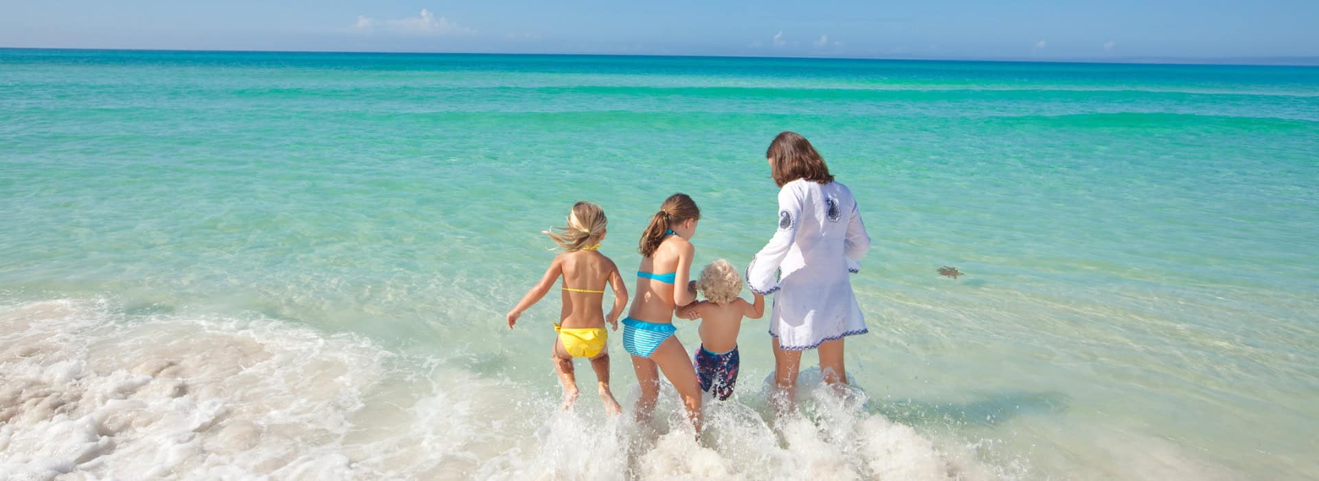 A family splashes in the beautiful clear green waters of scenic 30A in NW Florida.