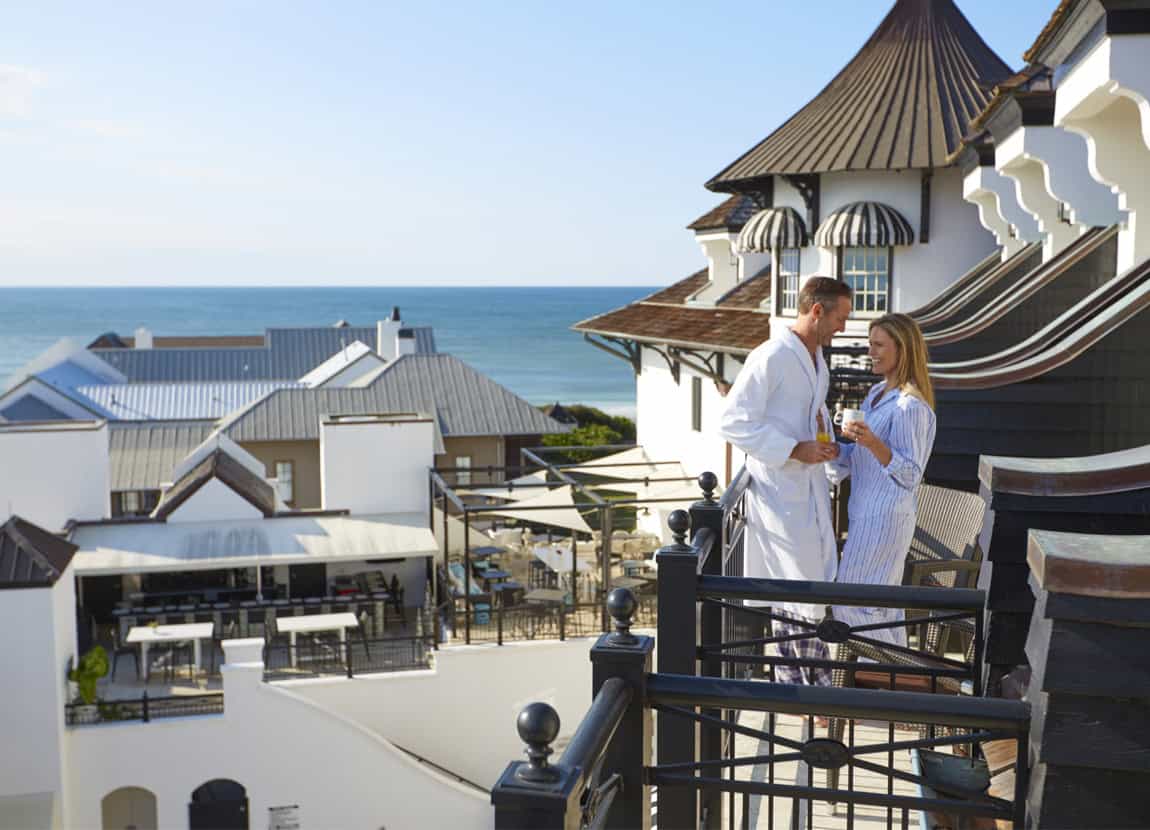 A couple on the balcony of The Pearl Hotel with the beach in the background.