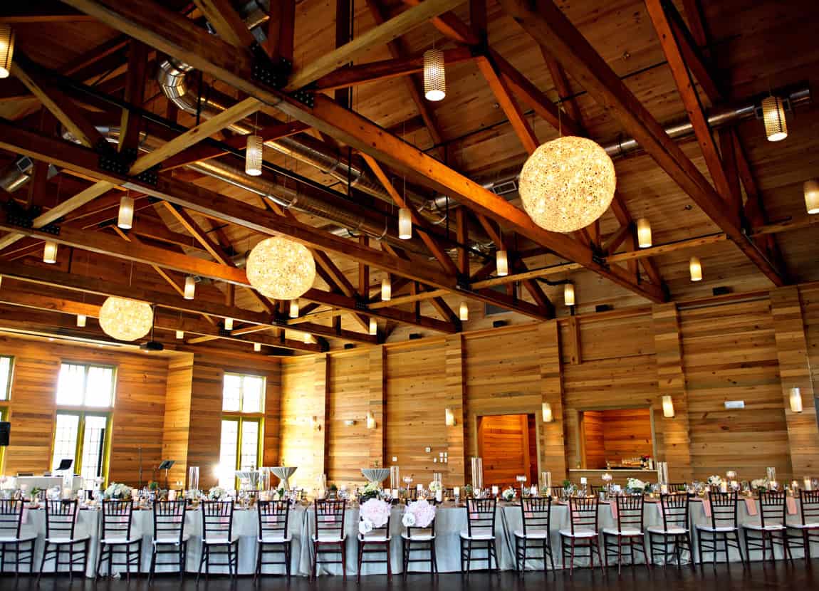 The wedding venue at watercolor inn with a large table and chairs set up for a wedding in a beautiful high ceiling rustic event space.