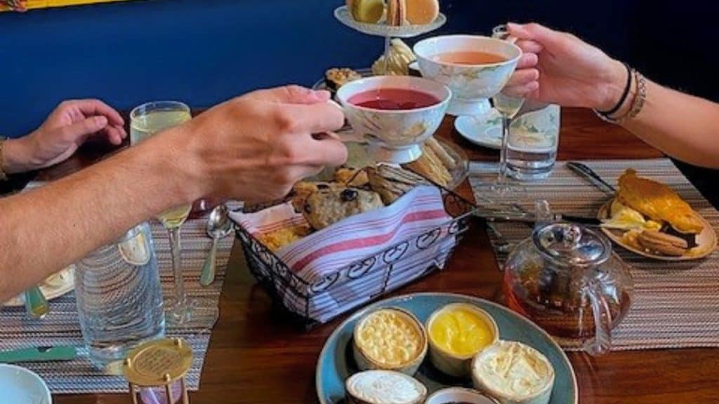 Two teacups cheering at Havana Beach bar surrounded by biscuits and pastries.